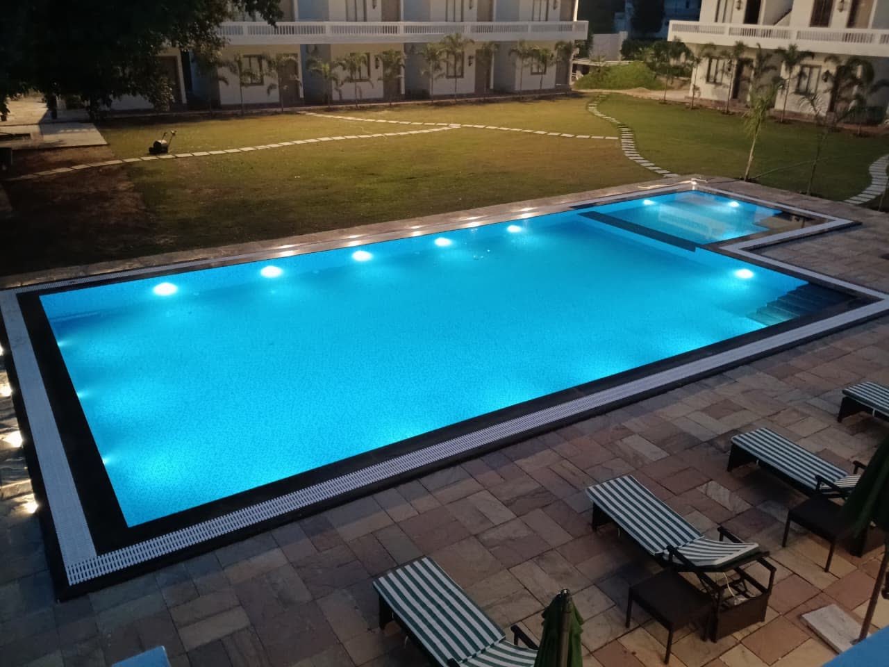 The lit pool and lawn at The Virasat after dark